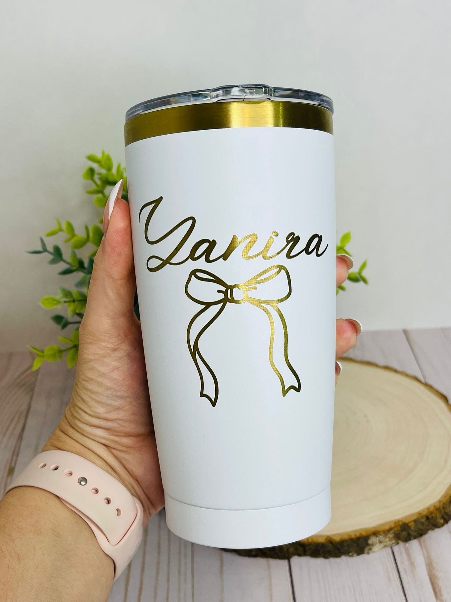 hand holding a personalized white tumbler engraved with name and a coquette bow